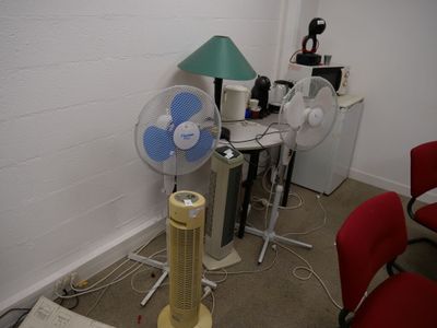 un ventilateur posé à côté d'une table sur laquelle se trouve une lampe
