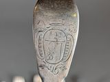 a silver spoon with a crest on it sitting on a table