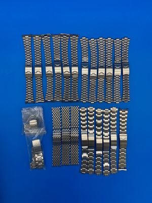 un gros plan sur un lot de bracelets en métal posés sur une surface bleue
