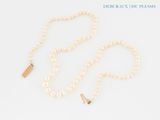 a close up of a pearl necklace with a gold clasp