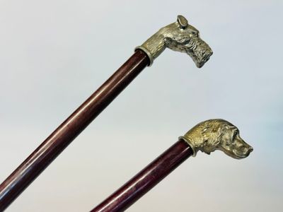 une paire de cannes de marche ornées de têtes de cheval sur fond blanc