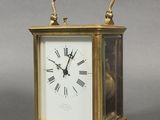 une petite horloge en laiton avec des chiffres romains sur le cadran