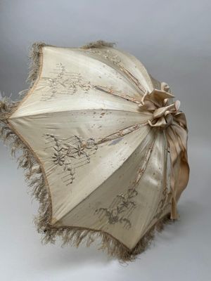 un parapluie blanc orné d'un ruban marron