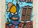 graffiti painting of a man painting a picture on a wall