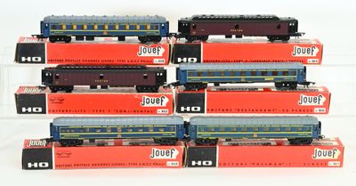 Plusieurs petits trains jouets sont empilés les uns sur les autres sur une surface blanche