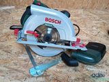 une scie circulaire Bosch posée par terre à côté d'autres outils