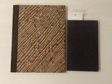 un petit carnet à la couverture noire posé à côté d'un bloc-notes