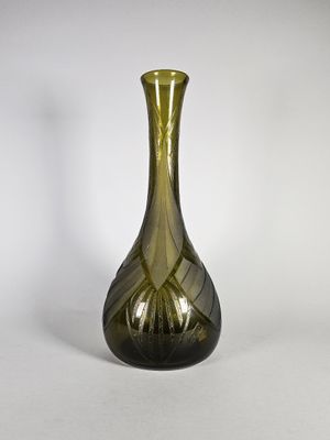 un vase en verre vert posé sur une surface blanche
