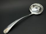 une cuillère en argent dont le manche repose sur une surface noire