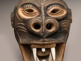 une image représentant un masque en bois avec des dents et des crocs