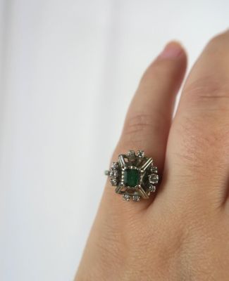 an image of a woman ' s hand holding a ring with a green stone on it