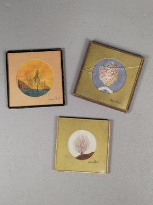 three small cards with paintings on them are sitting on a table