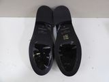 pair of black shoes on a white surface with a white wall in the background