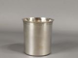 a close up of a silver cup on a gray surface
