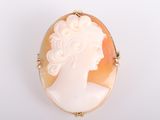 une image représentant le profil d'une femme sur une broche en forme de coquillage