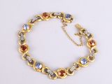 a close up of a gold bracelet with multi colored stones