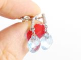 a person holding a pair of earrings with red and blue beads