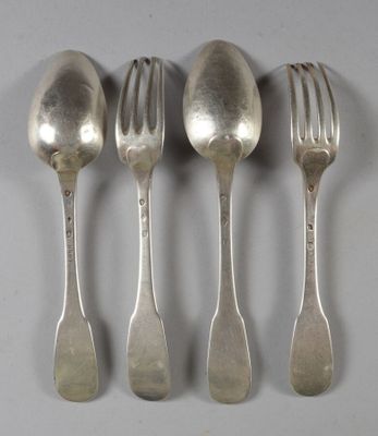 quatre cuillères en argent et une fourchette sont alignées sur une table