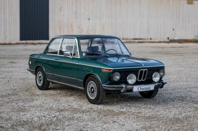 une voiture verte garée devant un immeuble