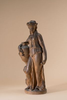 statue of a woman holding a vase and a vase on a beige background
