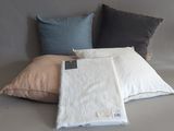 three pillows and a blanket on a bed with a tag on it