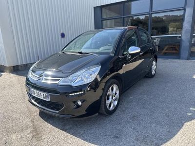 une voiture noire garée devant un immeuble, à côté d'un parking