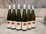 six bottles of wine sit on a table in front of a stone wall