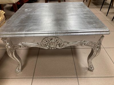 une table basse argentée posée sur un sol carrelé dans une pièce
