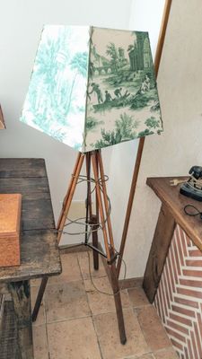 une lampe posée sur un trépied à côté d'une table
