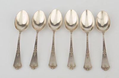six silver spoons are lined up in a row on a white surface
