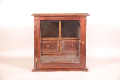 une image représentant un petit meuble en bois muni de tiroirs et d'une porte vitrée