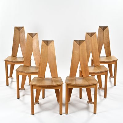 quatre chaises en bois sont alignées sur une surface blanche