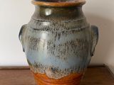 a blue and brown vase sitting on a wooden table