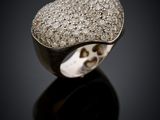 a close up of a heart shaped diamond ring on a black surface