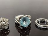 three rings and a ring with a blue topaz stone on a black surface