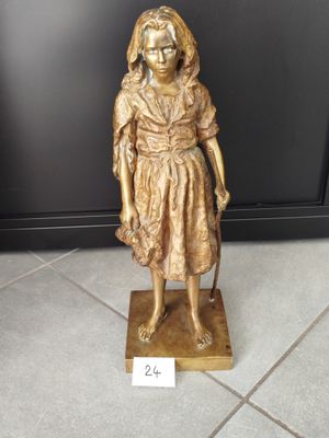 Une statue en or représentant une femme tenant une canne se dresse sur un sol carrelé