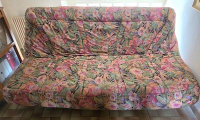 a futon couch that has a colorful floral cover on it