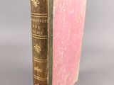 an old book with a pink cover sitting on top of a table