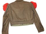 the back of a brown jacket with red pom poms on it