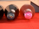 three bottles of wine are lined up on a red surface