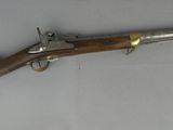 un vieux fusil au canon en bois et aux garnitures en laiton, posé sur une surface blanche