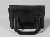 black leather handbag on white surface with a white background
