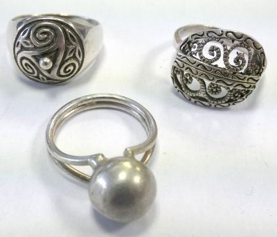 three silver rings and a silver ball on a white surface