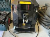 une machine à café posée sur un plan de travail, à côté d'une boîte à outils