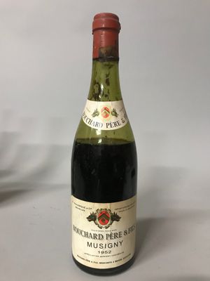 une bouteille de vin posée sur une table, à côté d'un verre de vin