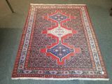 un tapis rouge et bleu posé sur une moquette verte dans une pièce