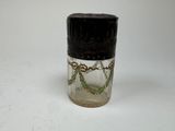 a small glass jar with a black lid on a white surface