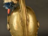 an antique gold helmet with a red and blue feather on top of it