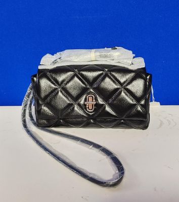 a small black purse with a chain strap on a table