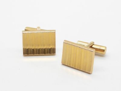 une paire de boutons de manchette en or sur fond blanc